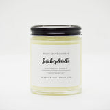 straight sided glass jar candle with black twist off metal lid and white label